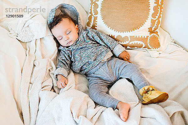 Kleiner Junge mit Kapuze schläft auf Decke