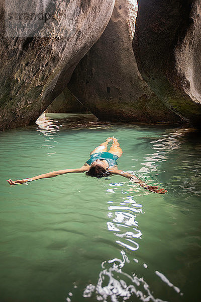 Junge Frau schwimmt auf dem Wasser in überfluteter Grotte  Virgin Gorda  Britische Jungferninseln