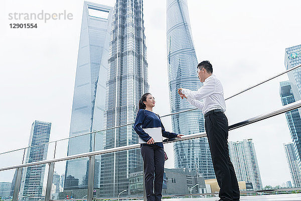 Junge Geschäftsfrau und Mann unterhalten sich im Finanzbezirk der Stadt  Shanghai  China