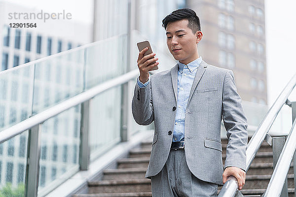 Junger Geschäftsmann betrachtet Smartphone auf Stadttreppe  Shanghai  China