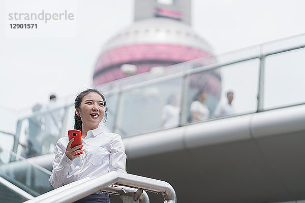 Junge Geschäftsfrau mit Smartphone auf der Stadttreppe  Shanghai  China