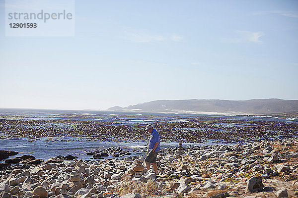 Tourist betrachtet Steinhaufen am Strand  Kapstadt  Westkap  Südafrika