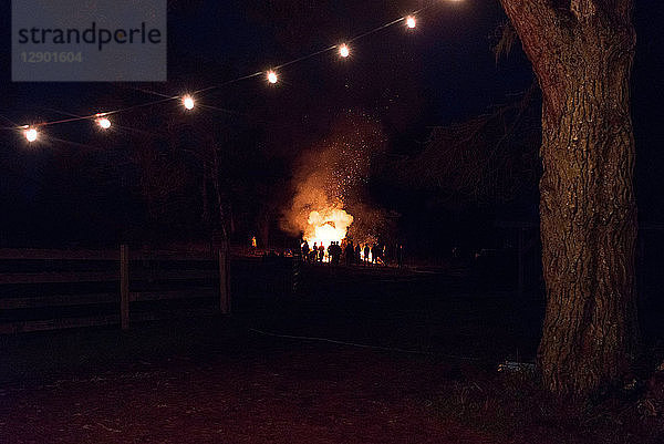 Silhouettenhafte Menschenmenge beobachtet nachts Lagerfeuer auf dem Feld