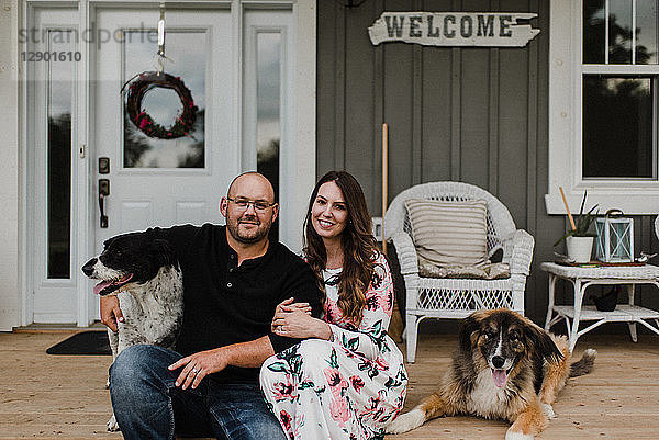 Ehepaar und ihre beiden Hunde sitzen auf der Veranda