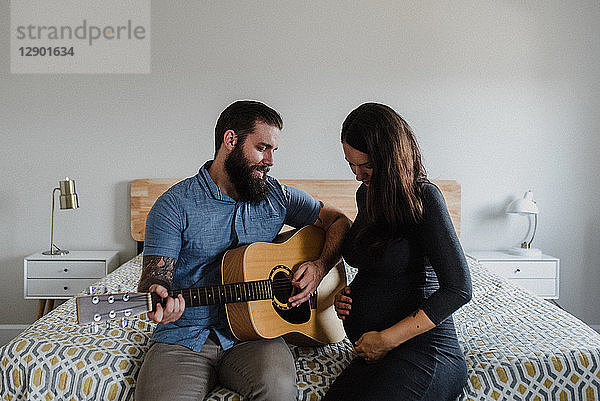 Mann spielt Gitarre für Baby im Bauch der Frau