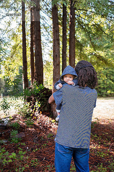 Erwachsener Mann trägt einen kleinen Sohn im Wald  Porträt
