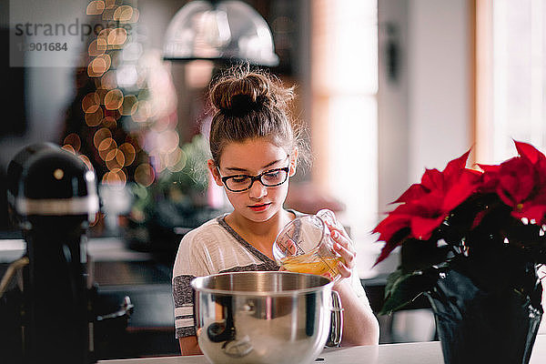 Mädchen gießt Eigelb in Rührschüssel für Weihnachtsplätzchen an der Küchentheke