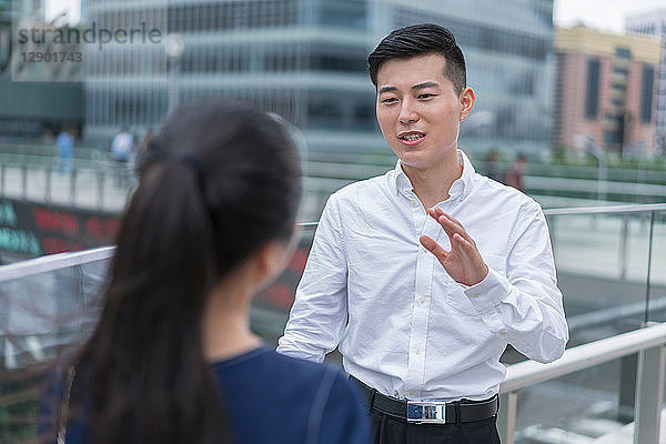 Junge Geschäftsfrau und Mann unterhalten sich auf dem Balkon im Finanzbezirk der Stadt  Shanghai  China