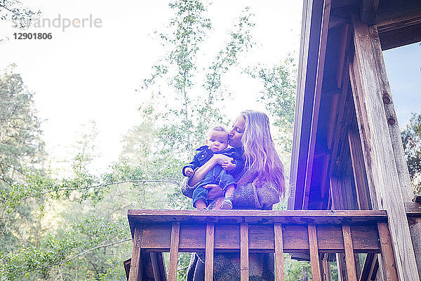 Mutter mit kleinem Sohn auf dem Balkon eines Holzhauses im Wald  Cazadero  Kalifornien  USA