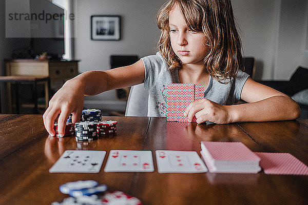 Mädchen spielen Karten am Tisch  stapeln Spielchips