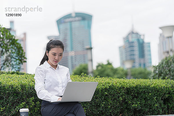 Junge Geschäftsfrau tippt am Laptop im Finanzbezirk der Stadt  Shanghai  China