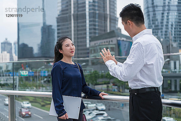 Junge Geschäftsfrau und Mann unterhalten sich auf dem Balkon im Finanzbezirk der Stadt  Shanghai  China