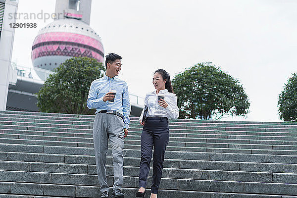 Junge Geschäftsfrau und Mann mit Kaffee zum Mitnehmen bewegen sich die Stadttreppe hinunter  Shanghai  China