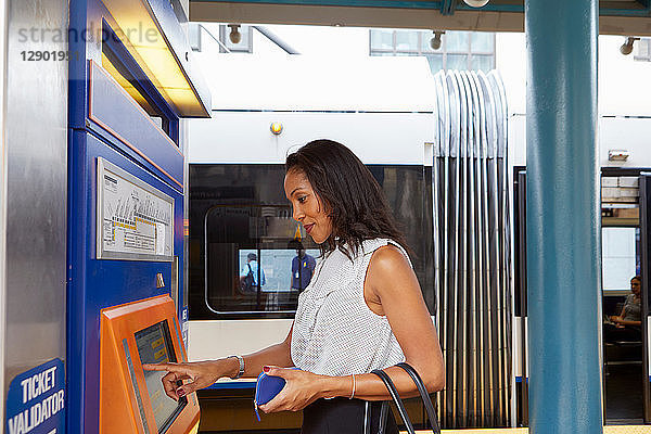 Geschäftsfrau kauft Zugfahrkarte am Automaten