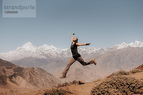 Frau springt auf den Gipfel  Annapurna Circuit  Himalaya  Dhaulagiri- und Tukuche-Gebirge im Hintergrund  Muktinath  Nepal