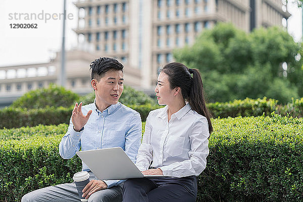 Junge Geschäftsfrau und junger Mann benutzen Laptop und plaudern am Sitz der Stadt  Shanghai  China