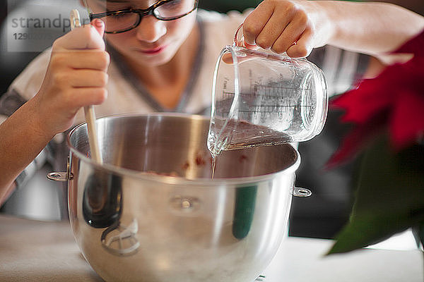 Mädchen gießt Eiweiß in die Rührschüssel für Weihnachtsplätzchen an der Küchentheke  Nahaufnahme