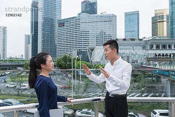 Junge Geschäftsfrau und Mann unterhalten sich auf dem Balkon im Finanzbezirk der Stadt  Shanghai  China