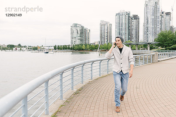 Junger Mann telefoniert beim Spaziergang am Deich entlang  Yaletown  Vancouver  Kanada