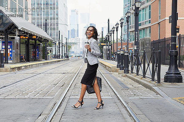 Geschäftsfrau überquert Stadtbahnschienen