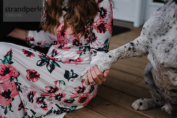 Frau und ihr Hund sitzen auf der Veranda