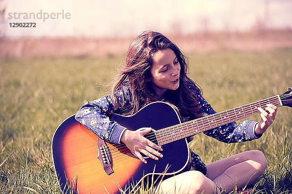 Mädchen spielt Gitarre auf Rasen