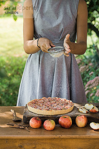 Frau bereitet Apfelkuchen auf dem Tisch zu
