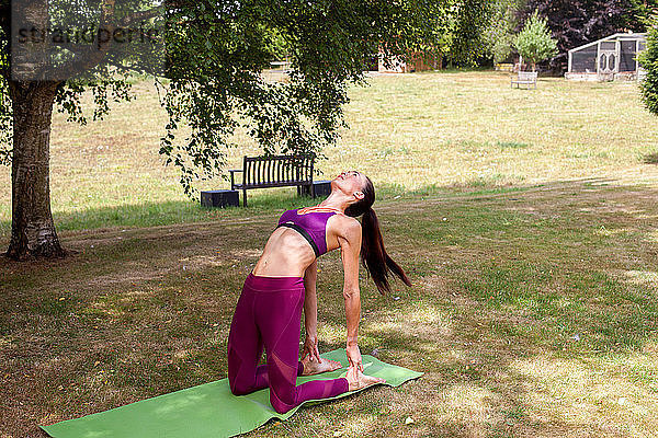 Frau praktiziert Yoga im Garten  bückt sich nach hinten