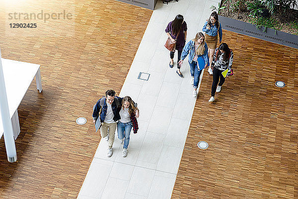 Männliche und weibliche Universitätsstudenten beim Gehen und Sprechen in der Universitätslobby  Hochwinkelansicht