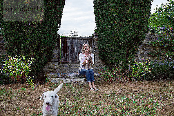 Reife Frau mit zwei Hunden im Garten sitzend  Porträt