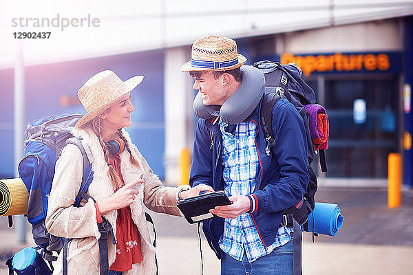 Rucksacktouristenpaar benutzt digitales Tablett am Flughafen