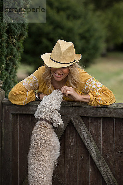 Frau spielt mit Haushund im Garten