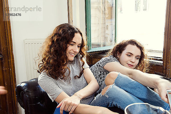 Zwei junge Freundinnen sitzen auf einem Sessel