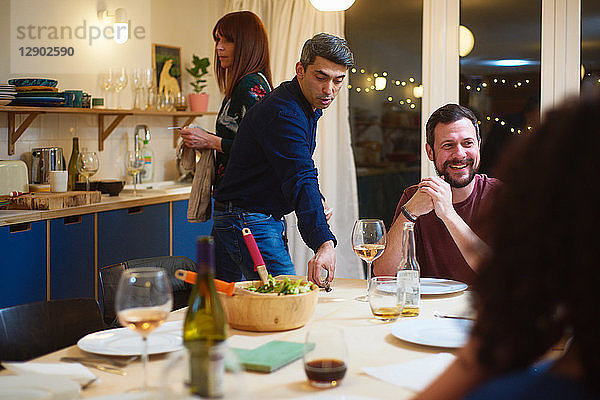 Freunde unterhalten sich  Mann deckt den Tisch bei der Dinnerparty
