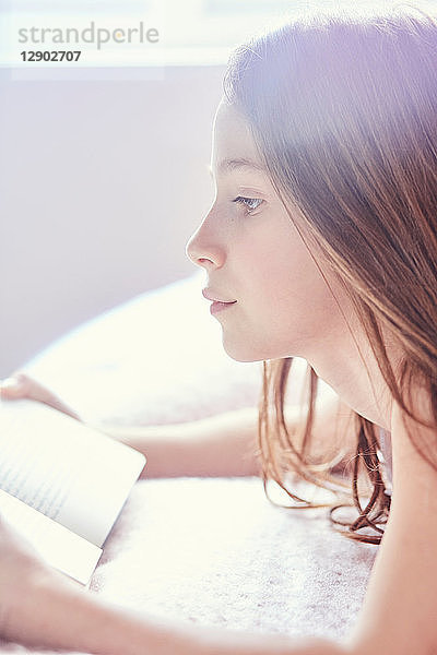 Mädchen liest Buch und träumt vor sich hin