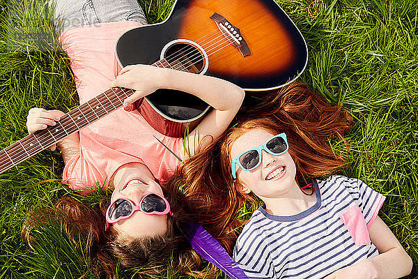 Mädchen spielen Gitarre auf Rasen