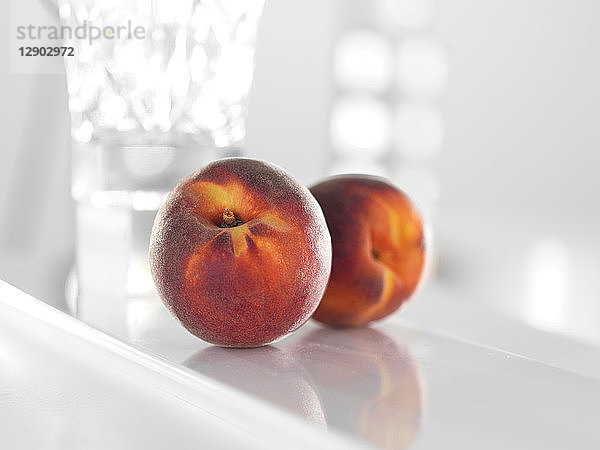 Pfirsiche auf glänzend weißer Oberfläche