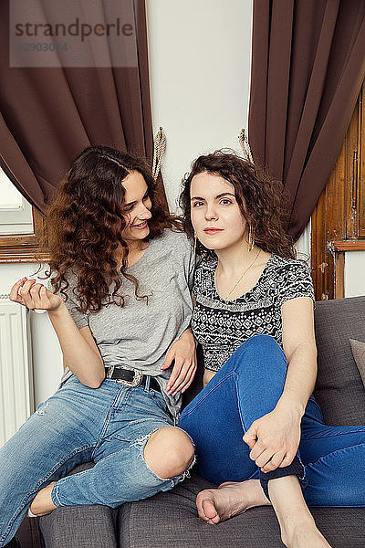 Zwei junge Freundinnen sitzen auf einem Sofa-Portrait