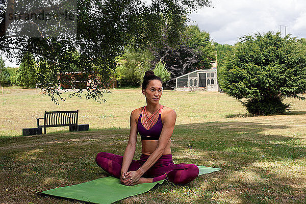 Frau praktiziert Yoga im Garten  macht eine Pause auf der Yogamatte