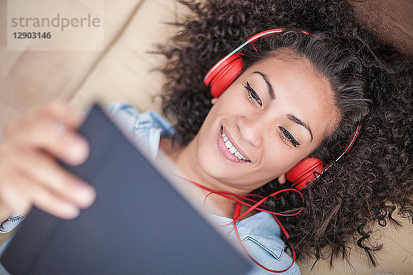 Frau hört zu Hause Musik auf digitalem Tablet