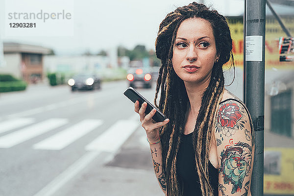 Frau benutzt Mobiltelefon am Straßenrand