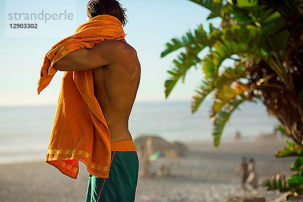 Männlicher Surfer im mittleren Erwachsenenalter  der sich am Strand abtrocknet  Camps Bay Beach  Kapstadt  Südafrika