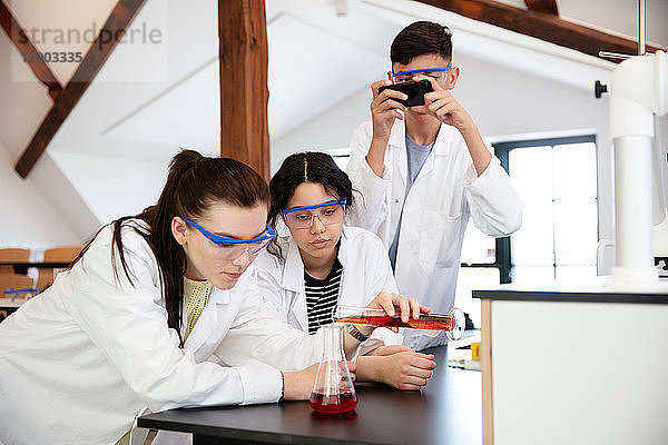 Schüler gießen im Labor eine Probe in einen Kolben