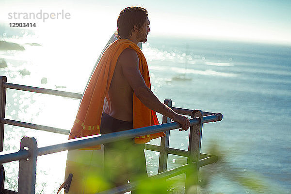 Männlicher Surfer im mittleren Erwachsenenalter  der vom Balkon auf das Meer schaut  Kapstadt  Camps Bay Beach  Kapstadt  Südafrika