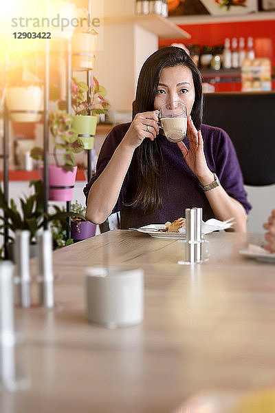 Mittlere erwachsene Frau trinkt Kaffee im Café