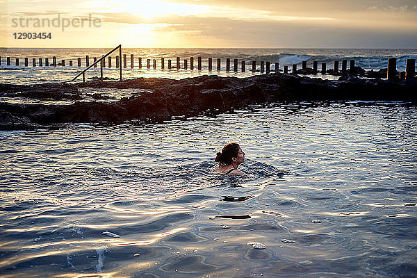 Frau schwimmt bei Sonnenuntergang im Küstenbecken  Las Palmas  Gran Canaria  Kanarische Inseln  Spanien