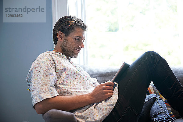 Mann benutzt digitales Tablett auf dem Sofa