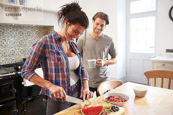 Ehepaar plaudert beim Schneiden von frischem Obst am Küchentisch