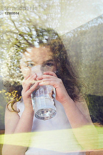 Junges Mädchen trinkt Wasser am Glasfenster