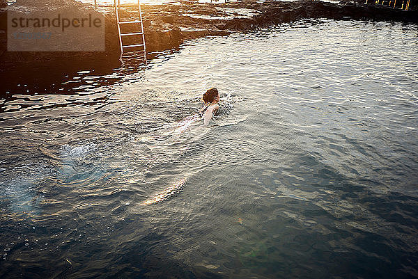 Frau schwimmt bei Sonnenuntergang im Küstenbecken  Las Palmas  Gran Canaria  Kanarische Inseln  Spanien